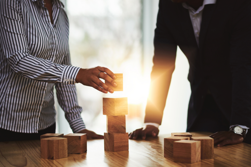 Two people stacking wooden blocks